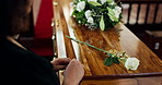 Coffin, flower and hands of wife at funeral for goodbye with grief, loss or pain of mourning closeup. Sad, death and rose for respect with woman in church for farewell ceremony or memorial service