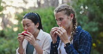 Friends, eating and relax on hike outdoors, conversation and healthy meal for break on trek in woods. Women, bonding and snack on holiday or vacation in forest, food and talking on travel in nature