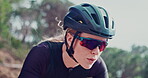 Woman, helmet and cycling for fitness outdoor, rider in sunglasses with race and workout in park. Serious, endurance and training with race or marathon in nature, cyclist for exercise and sports