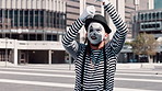 Mime, art and man in city with paint on face for performance, action and comedy outdoor. Artist, creativity and comic acting in urban street, wave hello in show and entertainment with mask for fun