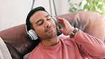 Rest, headphones and man on sofa at his home listening to music, radio or podcast online. Relax, technology and male person streaming album or song on website with cellphone in living room at house.