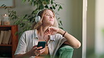 Woman, earphones and break with podcast, relax and rest at home or apartment living room. Lady, window and smartphone for learning, knowledge and story or information for happiness on sofa in lounge