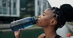 Fitness, training and happy black woman drinking water in a city for running, exercise or outdoor cardio. Sports, liquid and African female runner with drink for workout, hydration or body recovery