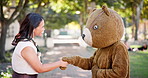 Bear, handshake and woman with costumer, greet and outdoor with hello and agreement with feedback. Halloween,  outfit and girl in a park, shaking hands and conversation with communication and review