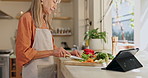 Cooking, tablet and mature woman with healthy food for salad, nutrition and cutting ingredients for lunch. Diet, vegetables and chef at kitchen counter with digital app, recipe and dinner at home