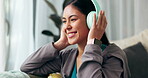 Music, headphones and sofa for happy woman, listening and radio or song streaming. Technology, podcast and audio or electronics in living room, happy and smile for relax Asian female person on couch