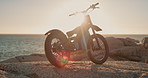 Beach, sunset and off road motorcycle for travel, adventure or extreme sport in nature at summer race. Transport, dirt bike or motorbike with ocean, mountain and challenge in power, speed and machine
