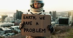 Astronaut, city and billboard with sign for earth, message or alert signal of news or problem on planet. Space traveler showing board or notification for crisis, awareness or protest in an urban town