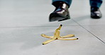 Office, fall and person with banana on floor for accident, medical emergency and injury from walking. Corporate, workplace safety and feet of worker slip on fruit for danger, law suit and risk