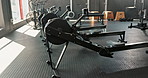Fitness, studio and gym with rowing machine for exercise, training and sports at health club. Steel, equipment and interior of empty fitness center with iron for workout, health and bodybuilding