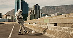 Bored astronaut, city and kicking with ball in street or waiting on sidewalk or road in an urban town. Space adventurer or traveler playing alone with round object on bridge to pass time on planet