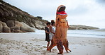Comic, people and dinosaur with costume for playing in beach or ocean, happiness and joy of women together. Outdoors, animal and girls moving or excited for fun, entertainment or cheerful dance