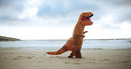 Dinosaur costume, beach and funny with sunshine, comic and running with waves and sand. Blue sky, Halloween outfit and humor with seaside and travel with vacation and nature with comedy and holiday