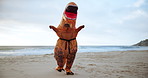 Beach, karate and person in dinosaur costume on sand by ocean or sea for fitness and training. Exercise, health and workout by water with adult athlete in t-rex outfit for discipline or self defense