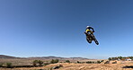 Blue Sky, male person and motorcycle jump with low angle for performance, extreme sports stunt and adrenaline. Competition, fearless and man on motorbike for outdoor challenge and freedom