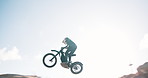 Jump, motorbike and biker in air or hill for training for extreme sports, safety and practice on sand. Sky, dirt or fearless person flying on motorcycle for off road race, risk or trick in challenge