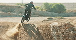 Speed, motorbike and person on hill in outdoor training for extreme sports, safety and practice on sand. Back, dirt or fearless driver on fast motorcycle for off road race, risk or trick in challenge