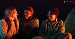 Friends, talking and laughing or camping at night with funny story, holiday adventure and cozy by bonfire in nature. Group, people and conversation by campfire for outdoor vacation and travel getaway