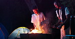 Night, campfire and friends smile with bbq, fist bump and fun chat at outdoor travel adventure in nature. Fire, meat and people camping together with tent, talking and relax at warm bonfire in dark