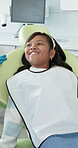 Dental care, oral hygiene and mouth with indian girl at dentist in chair for appointment or checkup. Consulting, healthcare and smile with happy child patient in medical clinic for teeth whitening