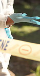 Tape, person and gloves on crime seen for investigation or evidence collection for analysis, inspection and outdoor. Forensics expert, protection gear and ready for detective work and observation.