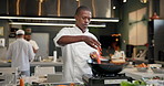 Add, black man or chef and pan on fire in kitchen for cooking with speed, professional and enhance flavor or taste. Person, serious and roast with flame for frying, gastronomy and culinary techniques