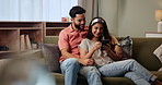 Happy, couple and relax on sofa with smartphone for streaming videos, social media memes and entertainment. Man, woman and together in home with cellphone for research for new apartments in Mumbai.