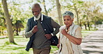 Interracial, senior couple and walking with partner in park for fitness, workout or cardio exercise. Man and woman taking a stroll in nature, road or street for outdoor training, health and wellness