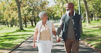 Love, happy and senior couple holding hands while walking in park with conversation, trust or bonding in nature. Interracial marriage, care or elderly people in forest with retirement, fun or travel