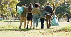 Group, plastic bag or people in park walking for waste management or recycling in community service. Back view, teamwork and volunteers cleaning garbage, junk or rubbish for nature sustainability