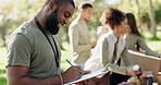 Charity, writing or man with clipboard for food donation, checklist or grocery stock management with team in forest. Community service, outreach or ngo volunteer with note planner for poverty support