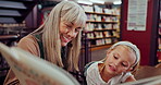 Girl, child and book with grandmother in library for education, growth and development with literature. Kid, senior woman and reading for learning, language and support with knowledge in bookshop