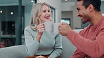 Happy couple, talking and drinking coffee in home living room for bonding, cheers or smile together. Man, woman and toast with tea for celebration, conversation or interracial people relax on sofa