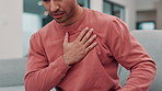 Man, hand and chest pain with injury, heart attack or ache on living room sofa at home. Closeup of male person in panic, cardiac arrest or stroke on couch from stress, anxiety or strain at house
