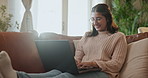Happy woman, relax and typing with laptop on sofa for online research, browsing or email at home. Female person, student or freelancer with smile on computer for communication or remote work at house
