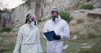 Forensic, inspector or team for outdoor investigation with clipboard, discussion or briefing with hazmat suit. Waste management, people or protection service in nature for safety or area disinfectant