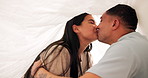 Love, kiss and home with sweet couple in blanket for romance, relationship or intimate together. Smile, marriage and young man with woman in bedroom for happiness, commitment or bonding in apartment
