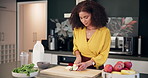 Happy, woman and cooking in kitchen with vegetables for nutrition, balanced diet and healthy food. Female person, chef and knife for meal preparation with fruit or organic produce for lunch at home