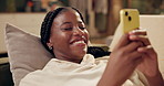 Happy, typing and black woman with phone on sofa for online chat, communication and networking. Relax, home and person on smartphone for social media, funny website and internet news in living room