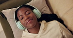 African woman, headphones and above on couch with smile, relax and peace with music in home living room. Girl, listening and happy for streaming, audio subscription and lying on lounge sofa in house