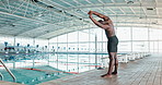 Arms, stretching and black man at swimming pool for exercise,  training or water sports in gym. Body, fitness and health with warm up of professional swimmer getting ready for competition or wellness