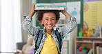 Child, face and book on head in school classroom for education learning in kindergarten, scholarship or happy. Kid, smile and knowledge academy for student creativity as reading, lesson or library