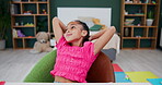 Little girl, relax and chair in home leisure after studying or school work, calm and happiness for weekend. Child, thinking and rest for comfort with thoughts for entertainment, daydream and unwind.