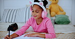 Child, headphones and girl with book in house, music and drawing or writing on bed for childhood development. Growth, creative sketch and education homework, online streaming and audio or listening