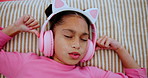 Headphones, relax and girl child on bed dancing to online music, radio or playlist at home. Calm, rest and young kid streaming song or album on internet with technology in bedroom at house from above