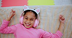 Headphones, relax and face of kid on bed dancing to online music, radio or playlist at home. Happy, rest and portrait of girl child streaming song or album on internet in bedroom at house from above.