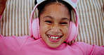 Headphones, happy and face of child on bed dancing to online music, radio or playlist at home. Smile, relax and portrait of girl kid streaming song or album on internet in bedroom at house from above