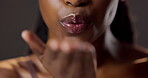 Hand, kiss and mouth with black woman flirting in studio on dark background for beauty or skincare. Blow, lips and love with smile of confident person closeup for affection, desire or romance