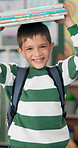 Books, balance and face of child in school ready for studying, lesson and learning in classroom. Textbooks on head, student and portrait of happy, excited and young boy for knowledge and education