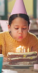 Girl, blow candles and birthday cake at kindergarten, happy and celebration with party hat, flame and food. Child, classroom and ideas for wish, dessert and excited for event at preschool academy